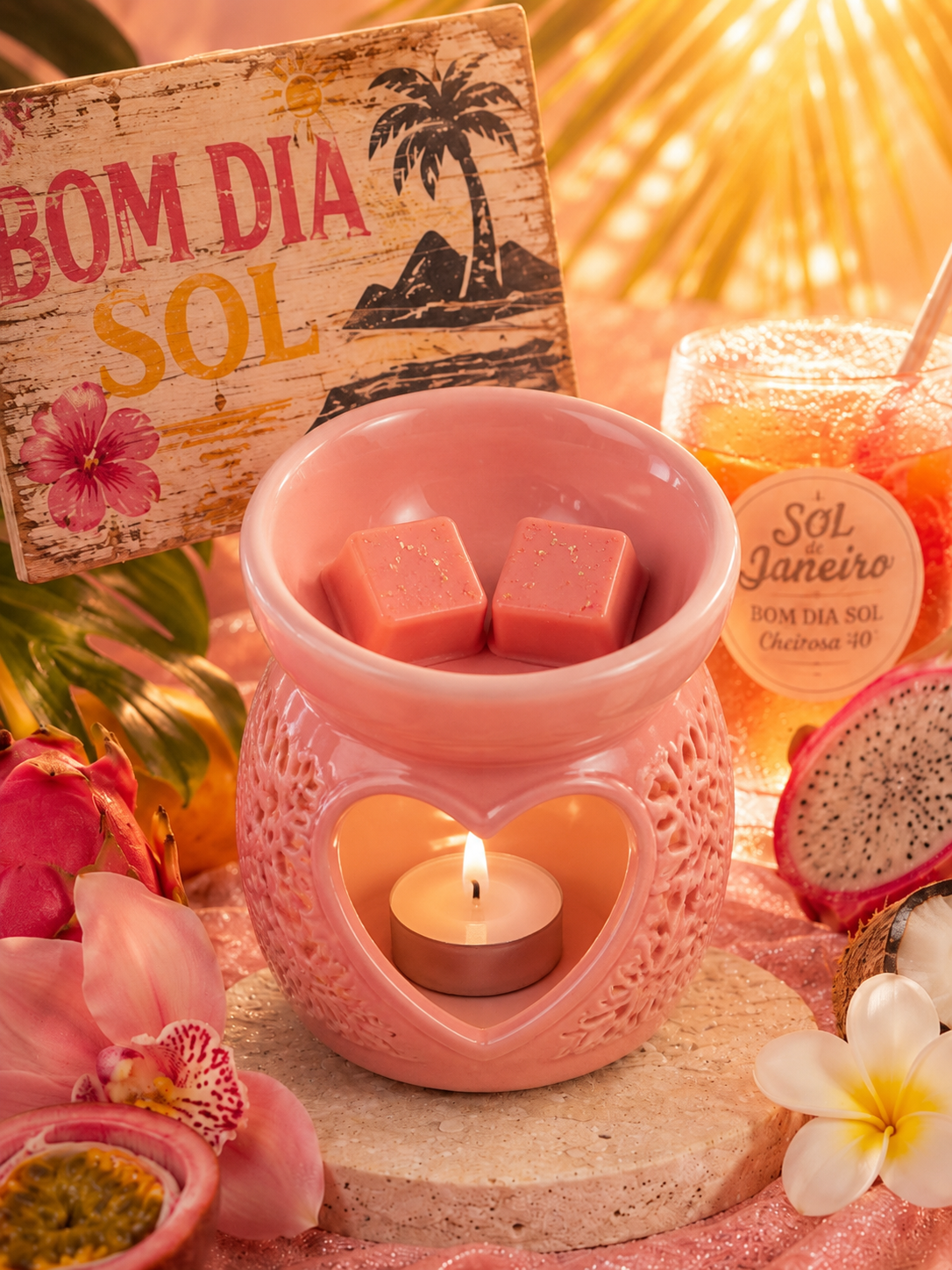 A pink ceramic heart-shaped wax warmer with a lit tealight candle inside, styled with pink wax cubes, tropical flowers, a sign reading 'BOM DIA SOL', and a jar labeled 'SOL Janeiro' in a warm, tropical setting.