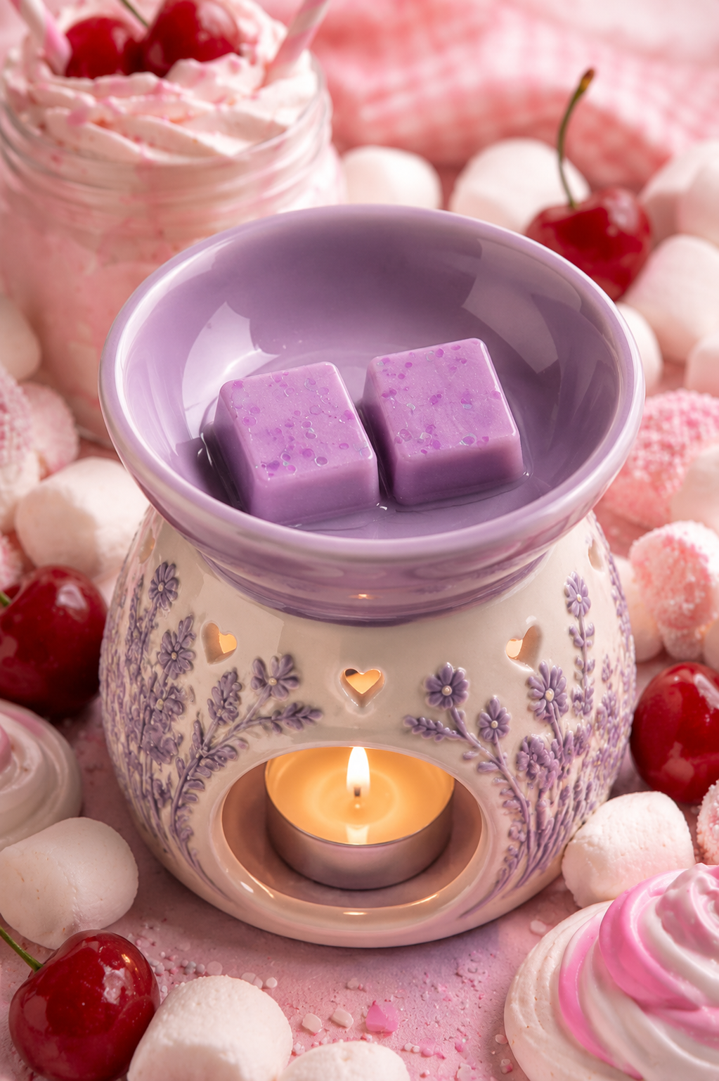Lavender wax warmer with a lit tea light candle inside, featuring two purple wax cubes in the bowl, surrounded by marshmallows, cherries, and pink whipped cream.