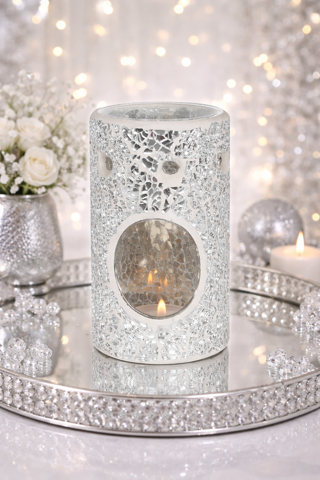 Decorative wax and oil burner with intricate design on a reflective surface with blurred lights in the background