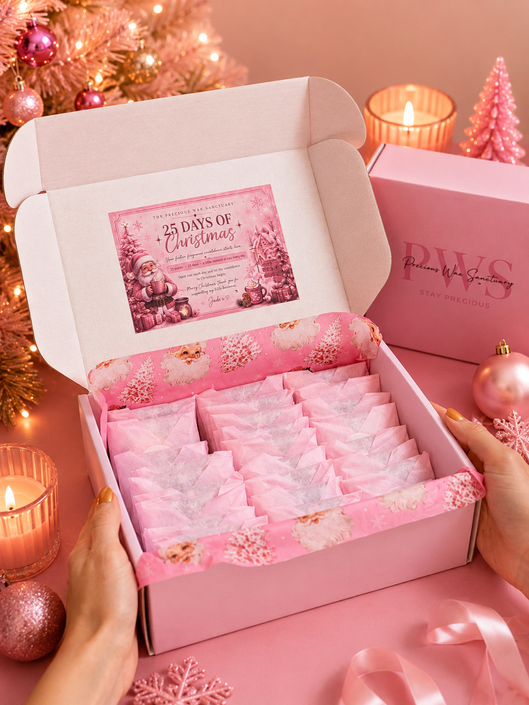 An open wax melt christmas advent calendar pink gift box held by two hands, filled with individually wrapped pink items and a printed holiday card inside. The box lid shows the brand name PWS and the text '25 Days of Christmas.