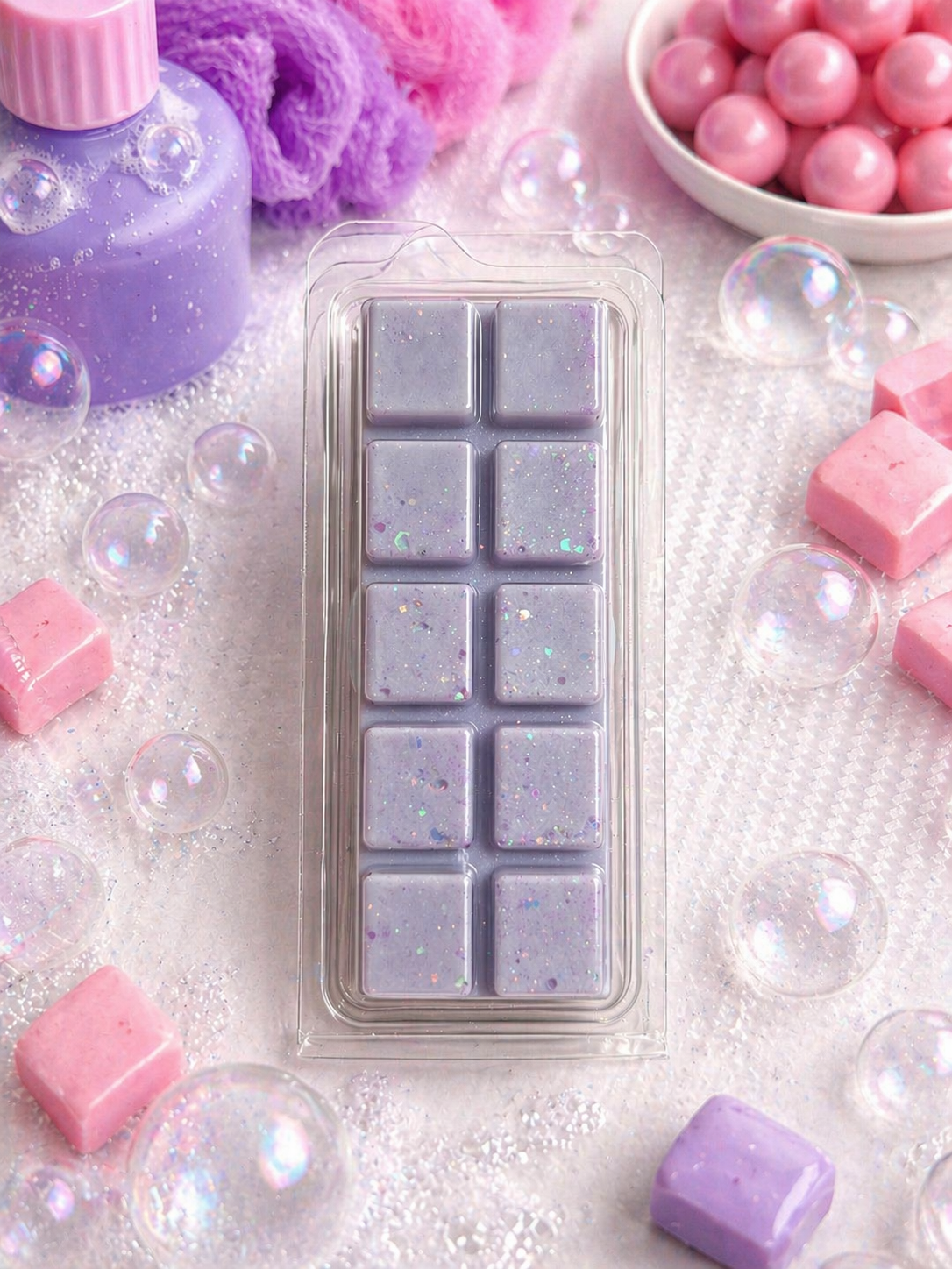 Rectangular mold with purple wax melts surrounded by pink wax bars and bubbles on a white background