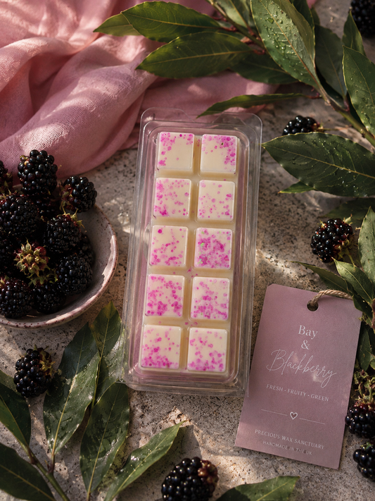 white wax melts with pink glitter, styled on a stone surface with blackberries, green leaves, a pink cloth, and a lavender tag reading 'Bay & Blackberry'.