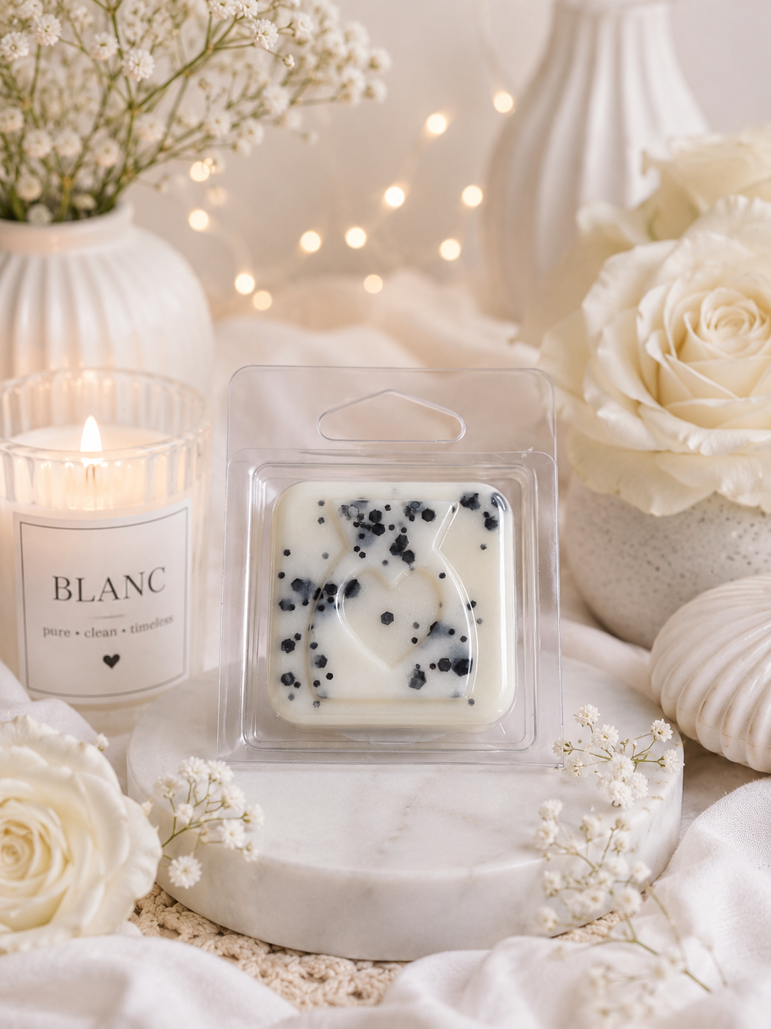 Candle wax melt package labeled 'BLANC' with a candle and flowers in the background