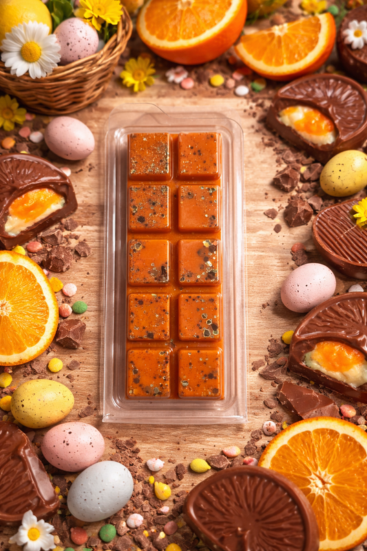 wax melt with Easter-themed decorations including oranges, eggs, and flowers on a wooden surface.