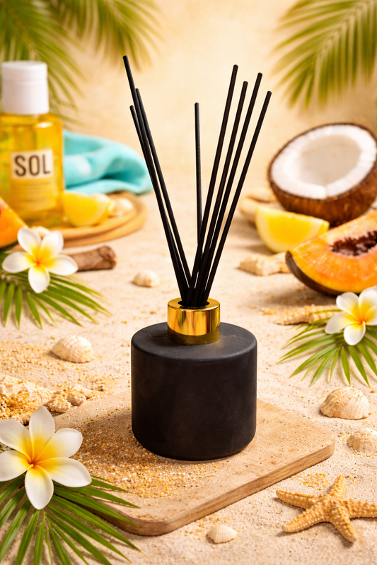 A amber diffuser with gold cap on a sandy surface with tropical elements like coconuts, flowers, and starfish.