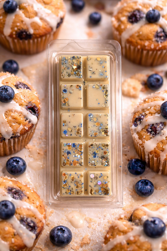 Packaged wax melts with decorative stones on a background of blueberry muffins.