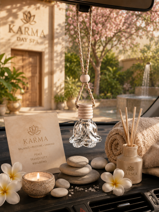 Karma Day Spa products including a diffuser, candles, and stones on a car diffuser with car dashboard with spa building in the background.
