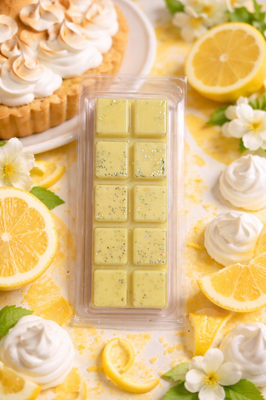 Pack of lemon-flavored wax melts surrounded by lemons and whipped cream on a decorative background