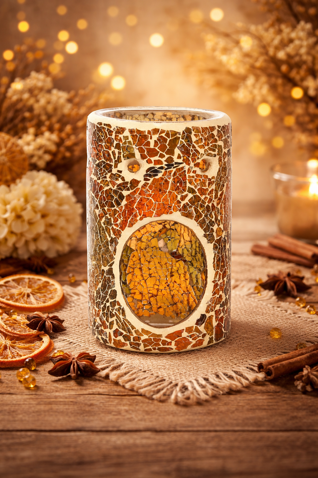 Decorative wax and oil holder with mosaic design on a wooden surface with autumn elements.