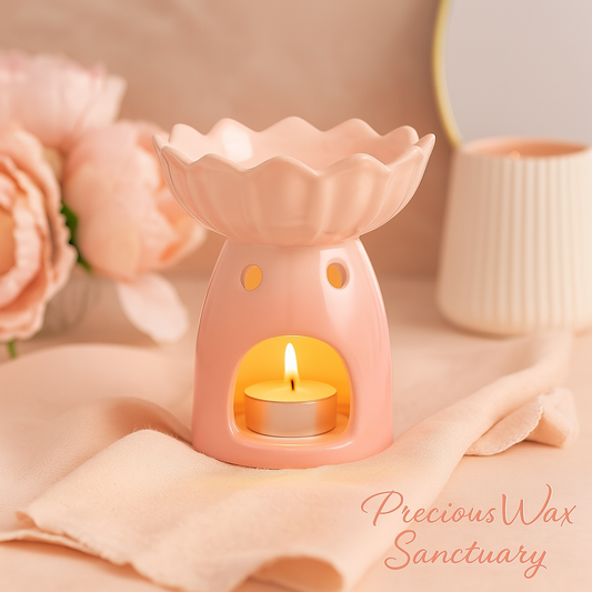 Pink wax warmer with a lit candle on a soft pink fabric background, featuring the brand 'Precious Wax Sanctuary'.