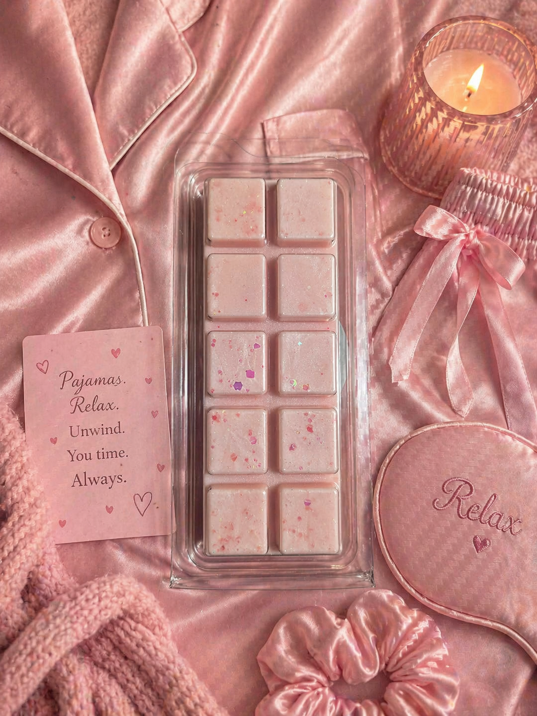 Wax Melts in a clear packaging with a card and pink satin items on a pink background