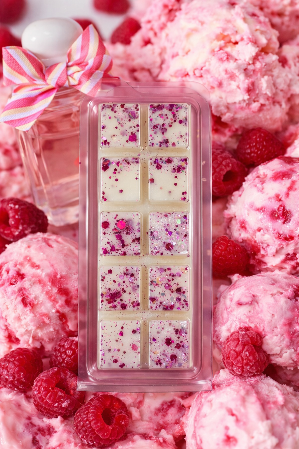 Pink wax melt bar with raspberry pieces surrounded by raspberries and a decorative bow.
