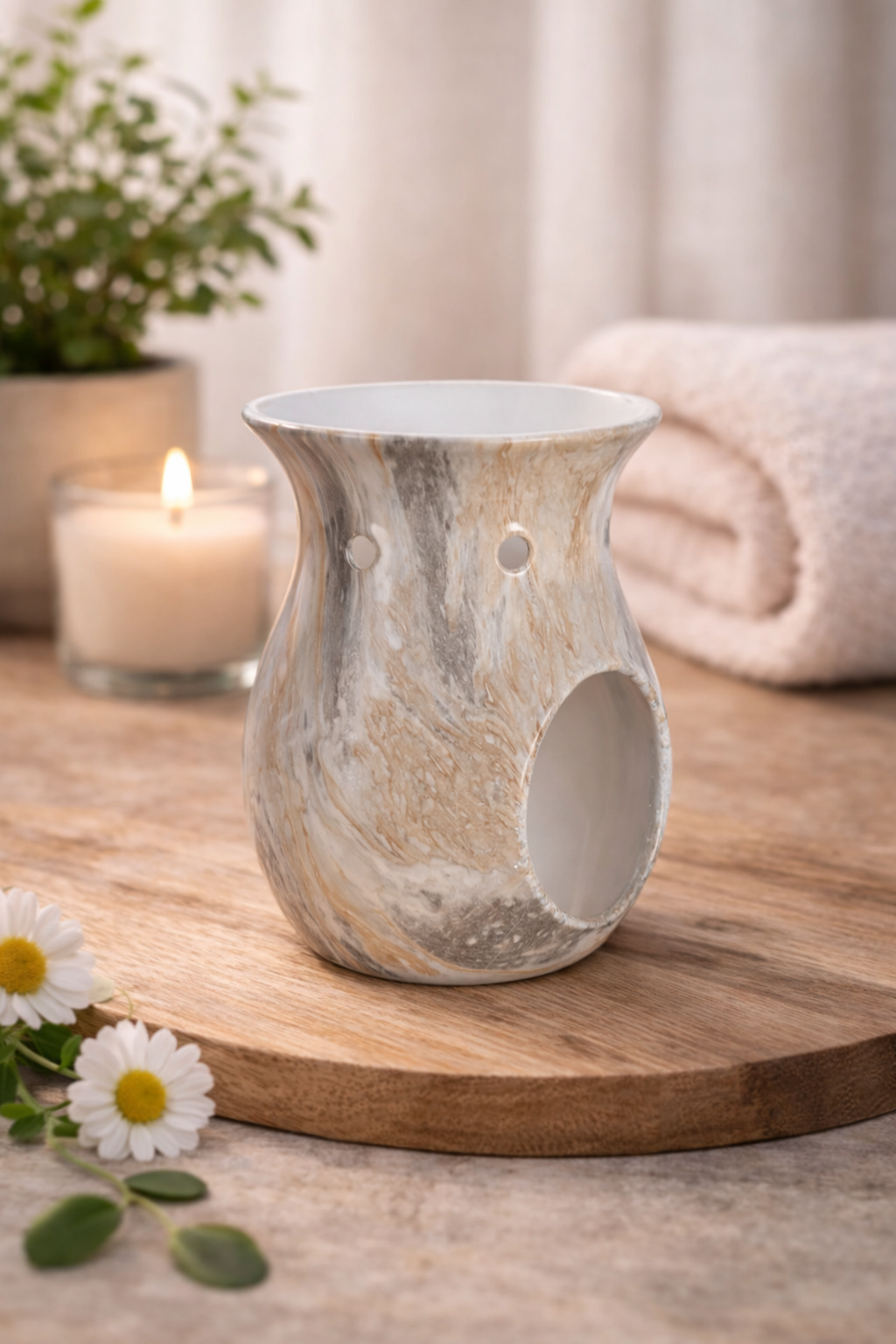Marble-patterned wax and oil burner on a wooden surface with a candle and flowers in the background