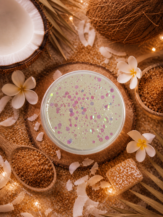 Toasted coconut sugar gel wax surrounded by coconut pieces, flowers, and lights on a wooden surface