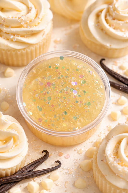 Small container of vanilla buttercream gel wax surrounded by vanilla cupcakes and vanilla beans.