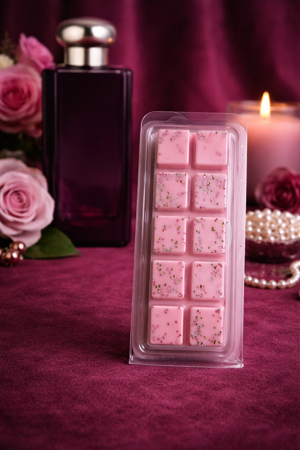 Packaged pink wax melts with a candle and roses on a purple background